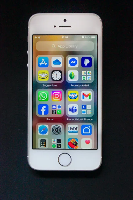 Close-up view of a smartphone showing a blurred image, sitting on a desk next to a laptop.
